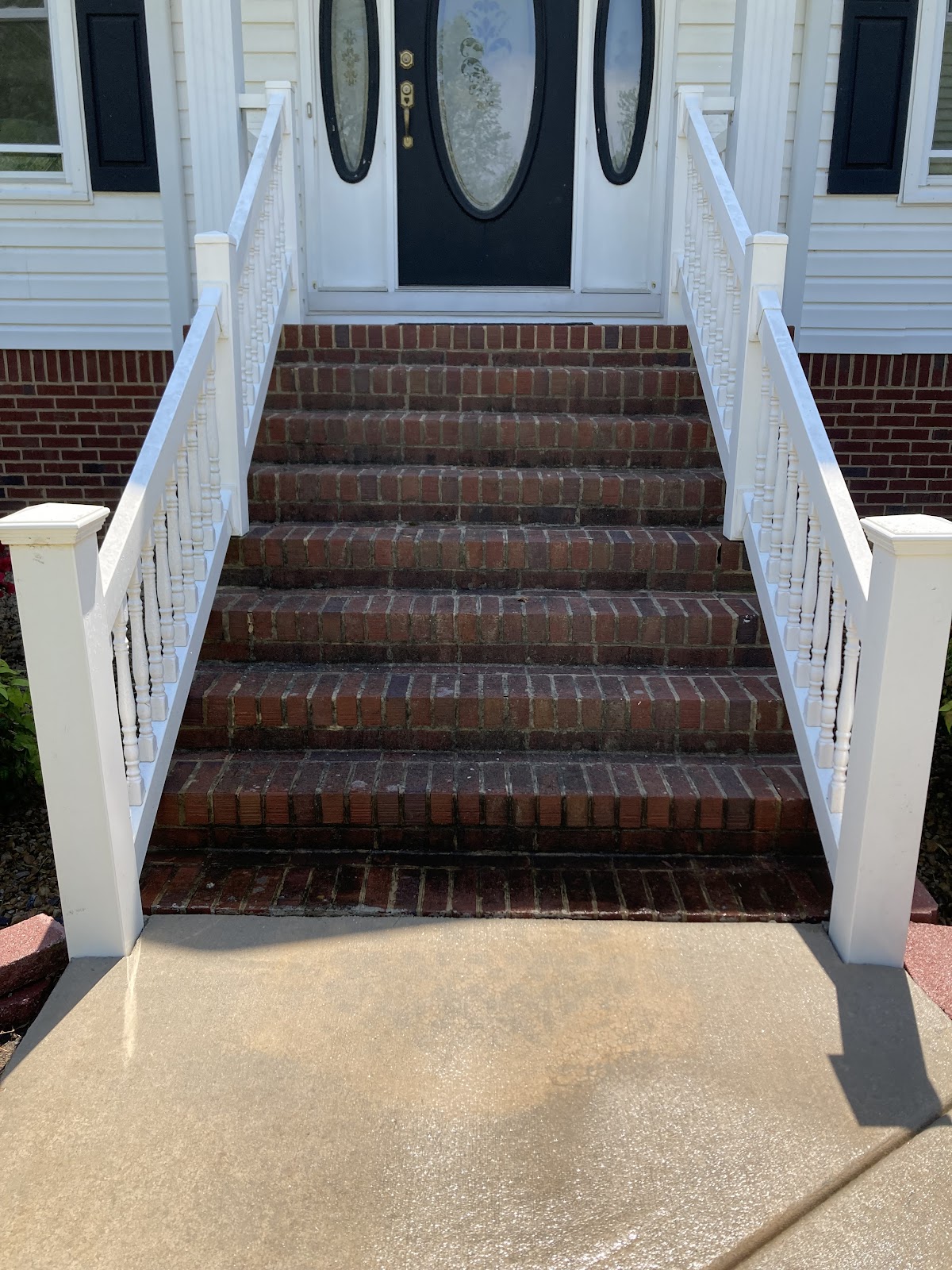 Brick steps with white rails and a freshly cleaned concrete landing